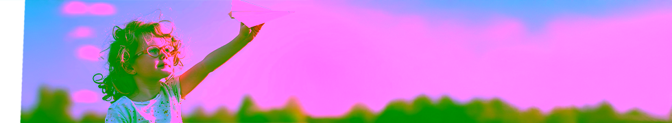 Zdjęcie małego dziecka z kręconymi włosami, które trzyma papierowy samolot skierowany w stronę nieba. Dziecko nosi jasną koszulkę z drobnymi wzorami, a w tle znajduje się plener z błękitnym niebem i zielenią. Ukazuje kreatywność, rozwój i bezpieczne warunki zabawy